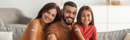 Smiling family of three with Band-Aids on upper arms indicating they have been vaccinated